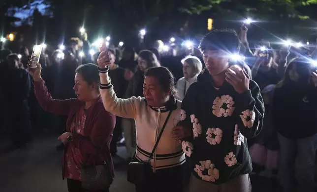 From left, Glenda Ahyeng, sister Liza Ahyeng and Shane Ahyeng hold cell phone lights during a vigil for victims after a vehicle drove into a crowd during a Filipino heritage festival in Vancouver, British Columbia, Sunday, April 27, 2025. (AP Photo/Lindsey Wasson)