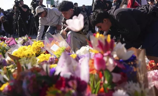 Visitors pay their respects at a memorial after a vehicle drove into a crowd during a Filipino heritage festival in Vancouver, British Columbia, Sunday, April 27, 2025. (AP Photo/Lindsey Wasson)