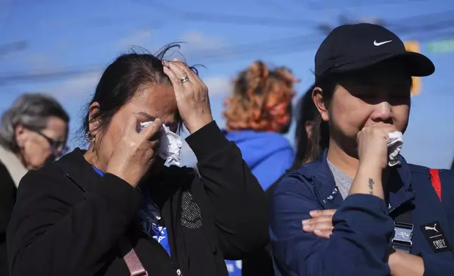 Two people react at a memorial after a vehicle drove into a crowd during a Filipino heritage festival in Vancouver, British Columbia, Sunday, April 27, 2025. (AP Photo/Lindsey Wasson)