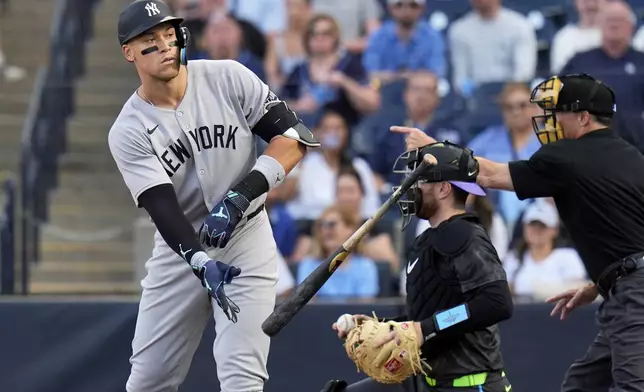 New York Yankees' Aaron Judge, left, flips his bat as he draws a walk from Tampa Bay Rays pitcher Drew Rasmussen during the first inning of a baseball game Friday, April 18, 2025, in Tampa, Fla. (AP Photo/Chris O'Meara)