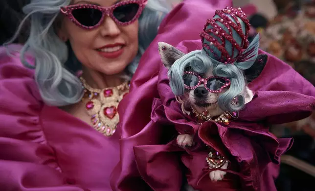A reveler wearing decorated hats and costumes hold her dog as she participates in the annual Easter Parade and Bonnet Festival in front of St. Patrick's Cathedral on Sunday, April 20, 2025, in New York. (AP Photo/Andres Kudacki)