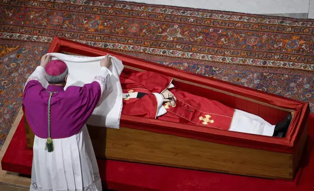 Vatican Master of Ceremonies Archbishop Diego Giovanni Ravelli covers the face of late Pope Francis with a silk cloth before closing his casket in St. Peter's Basilica at the Vatican Friday, April 25, 2025. (Vatican Media via AP)