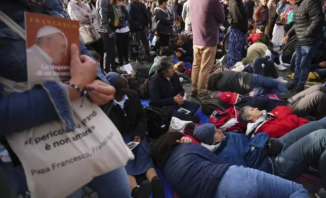 Faithful rest on the ground outside St Peter's Basilica waiting for the funeral of Pope Francis in St. Peter's Square at the Vatican, Saturday, April 26, 2025. (AP Photo/Andrew Medichini)