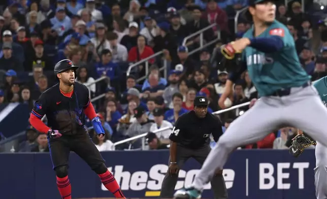 Toronto Blue Jays' George Springer (4) takes a lead off first base as Seattle Mariners starting pitcher Bryan Woo (22) throws to a Blue Jays batter in the second inning of a baseball game in Toronto on Friday, April 18, 2025. (Jon Blacker/The Canadian Press via AP)
