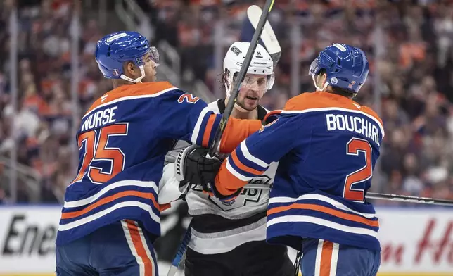 Los Angeles Kings' Adrian Kempe, center, Edmonton Oilers' Darnell Nurse (25) and OIlers' Evan Bouchard (2) rough it up during the first period of Game 3 of a first-round NHL hockey playoff series in Edmonton, Alberta, Friday, April 25, 2025. (Jason Franson/The Canadian Press via AP)