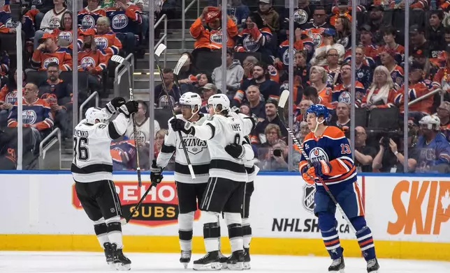 Los Angeles Kings players celebrate a goal as Edmonton Oilers' Mattias Janmark (13) skates past during the second period of an NHL hockey playoff game in Edmonton, Alberta, Friday, April 25, 2025. (Jason Franson/The Canadian Press via AP)