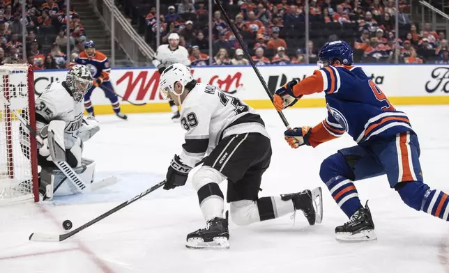 Los Angeles Kings' Jeff Malott (39) is chased by Edmonton Oilers' Jake Walman (96) as Kings' goalie Darcy Kuemper (35) follows the puck during the second period of an NHL hockey playoff game in Edmonton, Alberta, Friday, April 25, 2025. (Jason Franson/The Canadian Press via AP)