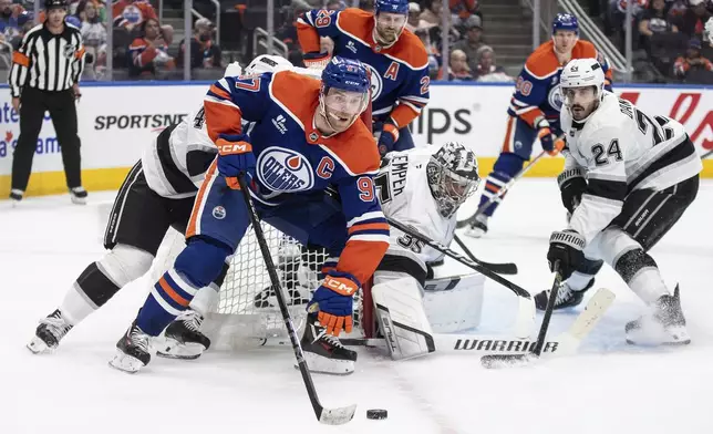 Los Angeles Kings' goalie Darcy Kuemper (35) looks for the puck as Edmonton Oilers' Connor McDavid (97) skates around the net and Kings' Phillip Danault (24) defends during the second period of an NHL hockey playoff game in Edmonton, Alberta, Friday, April 25, 2025. (Jason Franson/The Canadian Press via AP)