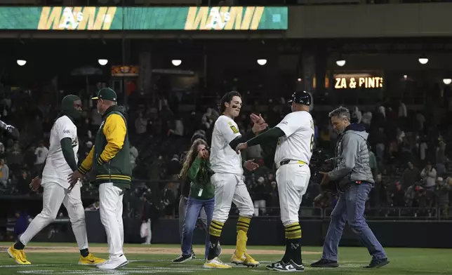 Athletics Jacob Wilson, middle, and first base coach Bobby Crosby right, high five after Wilson walk off single against the Texas Rangers in a baseball game Thursday, April 24, 2025, in West Sacramento, Calif. (AP Photo/Scott Marshall)