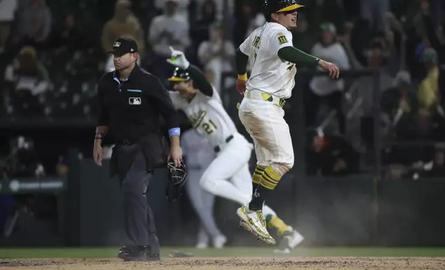 Athletics Luis Urías, right, slides into home safely to score the game winning run against the Texas Rangers during the ninth inning of a baseball game Thursday, April 24, 2025, in West Sacramento, Calif. (AP Photo/Scott Marshall)