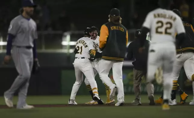 Athletics celebrate Jacob Wilson's (5) walk-off single against the Texas Rangers during the ninth inning of a baseball game Thursday, April 24, 2025, in West Sacramento, Calif. (AP Photo/Scott Marshall)