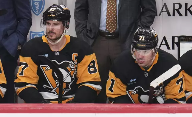 Pittsburgh Penguins' Sidney Crosby (87), and Evgeni Malkin sit on the bench during the third period of an NHL hockey game against the Boston Bruins in Pittsburgh, Sunday, April 13, 2025. (AP Photo/Gene J. Puskar)