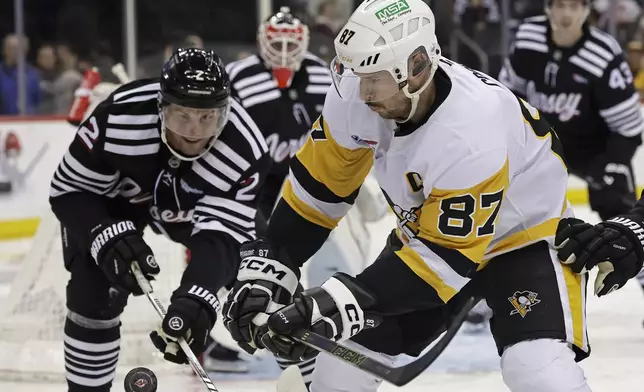 Pittsburgh Penguins center Sidney Crosby (87) battles for the puck with New Jersey Devils defenseman Brian Dumoulin in the third period of an NHL hockey game Friday, April 11, 2025, in Newark, N.J. (AP Photo/Adam Hunger)