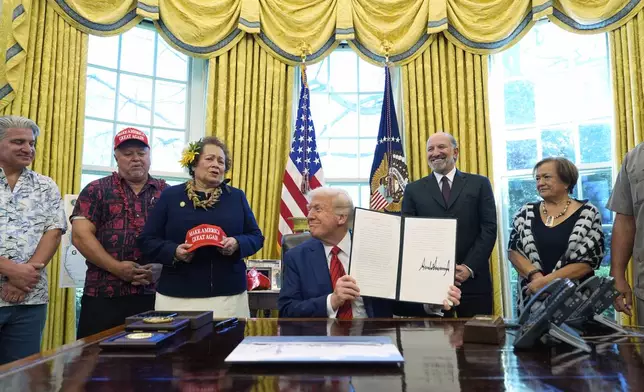 President Donald Trump holds a signed proclamation regarding commercial fishing in the Pacific as he speaks in the Oval Office of the White House, Thursday, April 17, 2025, in Washington. (AP Photo/Alex Brandon)