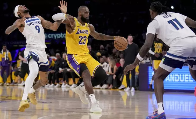Los Angeles Lakers forward LeBron James (23) dribbles against Minnesota Timberwolves guard Nickeil Alexander-Walker (9) and center Naz Reid (11) during the first half of Game 2 of an NBA first-round playoff series in Los Angeles, Tuesday, April 22, 2025. (AP Photo/Eric Thayer)