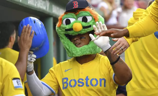 Boston Red Sox's Rafael Devers, center, wears a mascot mask as he celebrates his three-run home with teammates in the dugout in the fifth inning of a baseball game against the Chicago White Sox, Saturday, April 19, 2025, in Boston. (AP Photo/Steven Senne)