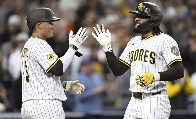 San Diego Padres' Fernando Tatis Jr., right, is congratulated by Manny Machado, left, after hitting a solo home run during the third inning of a baseball game against the Chicago Cubs, Monday, April 14, 2025, in San Diego, Calif. (AP Photo/Denis Poroy)