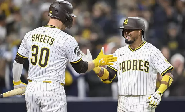San Diego Padres' Luis Arraez (4), right, is congratulated by Gavin Sheets (30) after hitting a solo home run during the eighth inning of a baseball game against the Chicago Cubs Monday, April 14, 2025, in San Diego, Calif. (AP Photo/Denis Poroy)