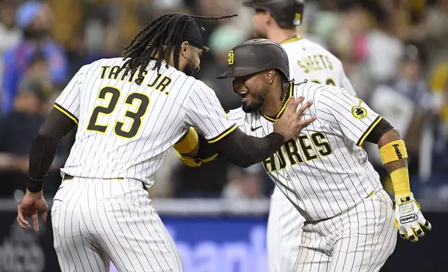 San Diego Padres' Luis Arraez, right, is congratulated by Fernando Tatis Jr. (23) after hitting a solo home run during the eighth inning of a baseball game against the Chicago Cubs, Monday, April 14, 2025, in San Diego, Calif. (AP Photo/Denis Poroy)