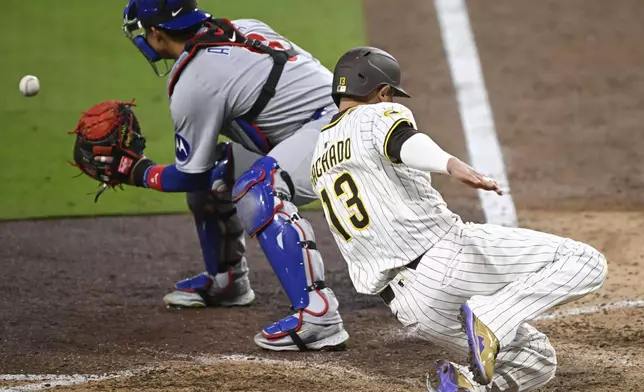 San Diego Padres' Manny Machado (13) scores ahead of the throw to Chicago Cubs catcher Miguel Amaya (9) during the seventh inning of a baseball game against the Chicago Cubs Monday, April 14, 2025, in San Diego, Calif. (AP Photo/Denis Poroy)