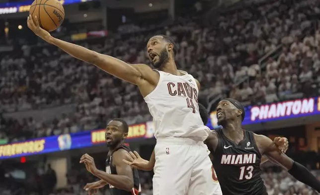 Cleveland Cavaliers forward Evan Mobley (4) reaches for a rebound between Miami Heat forward Andrew Wiggins, left, and center Bam Adebayo (13) in the first half in Game 2 of an NBA first-round playoff series, Wednesday, April 23, 2025, in Cleveland. (AP Photo/Sue Ogrocki)