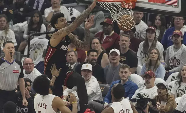 Miami Heat center Kel'el Ware, left, dunks over Cleveland Cavaliers center Jarrett Allen (31) and forward Evan Mobley, right, in the first half in Game 2 of an NBA first-round playoff series, Wednesday, April 23, 2025, in Cleveland. (AP Photo/Sue Ogrocki)