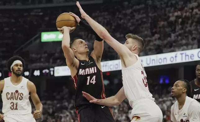 Miami Heat guard Tyler Herro (14) is defended by Cleveland Cavaliers forward Dean Wade, right, in the first half in Game 2 of an NBA first-round playoff series, Wednesday, April 23, 2025, in Cleveland. (AP Photo/Sue Ogrocki)