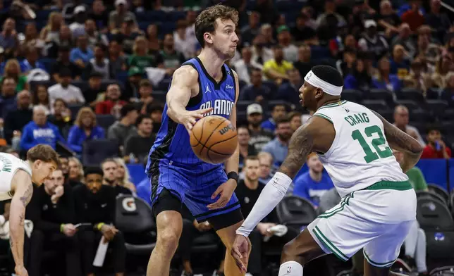 Orlando Magic forward Franz Wagner, left, passes the ball around Boston Celtics forward Torrey Craig (12) during the first half of an NBA basketball game, Wednesday, April 9, 2025, in Orlando, Fla. (AP Photo/Kevin Kolczynski)