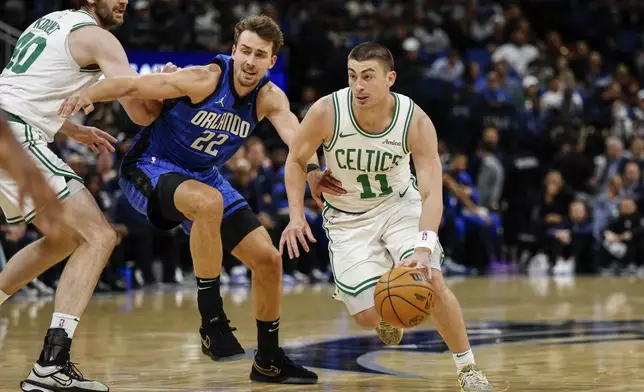 Orlando Magic forward Franz Wagner (22) fights through the screen by Boston Celtics center Luke Kornet, left, as he guards Boston Celtics guard Payton Pritchard (11) during the first half of an NBA basketball game, Wednesday, April 9, 2025, in Orlando, Fla. (AP Photo/Kevin Kolczynski)