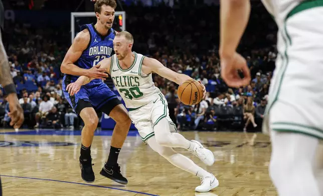 Boston Celtics forward Sam Hauser (30) drives against Orlando Magic forward Franz Wagner, left, during the first half of an NBA basketball game, Wednesday, April 9, 2025, in Orlando, Fla. (AP Photo/Kevin Kolczynski)