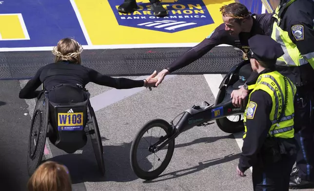 Marcel Hug, of Switzerland, right, congratulates Susannah Scaroni, of the United States, after winning the men's and women's wheelchair divisions during the Boston Marathon, Monday, April 21, 2025, in Boston. (AP Photo/Charles Krupa)