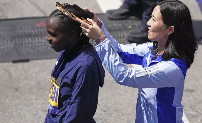 Sharon Lokedi, of Kenya, dons a wreath by Boston Mayor Michelle Wu after winning the women's division of the Boston Marathon, Monday, April 21, 2025, in Boston. (AP Photo/Charles Krupa)