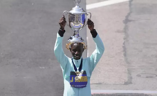 Boston Marathon winner John Korir, of Kenya, hoists the trophy while celebrating after the race, Monday, April 21, 2025, in Boston. (AP Photo/Charles Krupa)