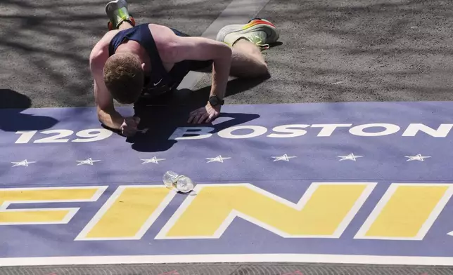 Runner Matthew Nawn crawls to cross the finish line during the Boston Marathon, Tuesday, April 22, 2025, in Boston. (AP Photo/Charles Krupa)