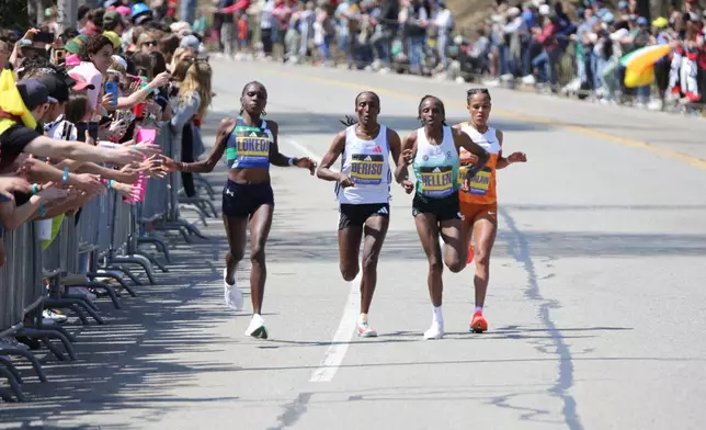 Boston Marathon winner Sharon Lokedi high-fives spectators in front of Boston College in Newton, Mass. while in the lead group of runners Monday, April 21, 2025. (AP Photo/ Jennifer McDermott)