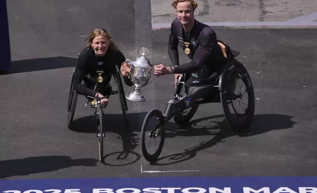 Marcel Hug, of Switzerland, right, and Susannah Scaroni, of the United States, hold up the winner's trophy after winning the men's and women's wheelchair divisions during the Boston Marathon, Monday, April 21, 2025, in Boston. (AP Photo/Charles Krupa)