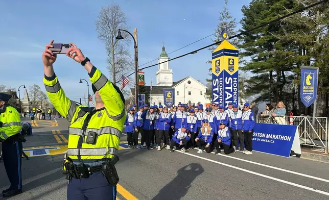 State Police Trooper Cory Hetu takes a selfie with the group of race volunteers at the start of the Boston Marathon Monday, April 21, 2025 in Hopkinton, Mass. (AP Photo/ Jennifer McDermott)