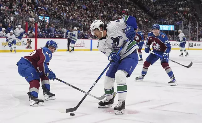 Vancouver Canucks left wing Kiefer Sherwood, front right, drives between Colorado Avalanche defenseman Samuel Girard, left, and left wing Jimmy Vesey (26) in the second period of an NHL hockey game Thursday, April 10, 2025, in Denver. (AP Photo/David Zalubowski)