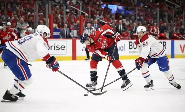Washington Capitals center Nic Dowd (26) battles for the puck against Montreal Canadiens left wing Emil Heineman (51) and defenseman David Savard (58) in the first period of Game 2 of a first-round NHL hockey playoff series Wednesday, April 23, 2025, in Washington. (AP Photo/Nick Wass)