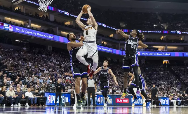 Denver Nuggets guard Christian Braun (0) goes up for a layup as Sacramento Kings forward Trey Lyles, left, defends during the first half of an NBA basketball game Wednesday, April 9, 2025, in Sacramento, Calif. (AP Photo/Sara Nevis)
