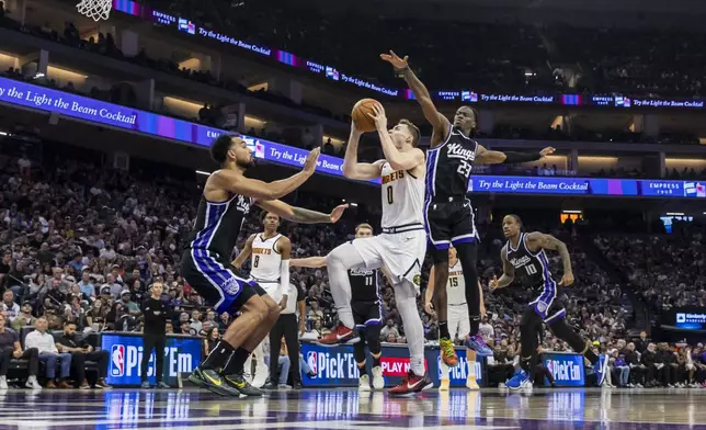 Denver Nuggets guard Christian Braun (0) goes up for a layup as Sacramento Kings forward Trey Lyles, left, defends during the first half of an NBA basketball game Wednesday, April 9, 2025, in Sacramento, Calif. (AP Photo/Sara Nevis)