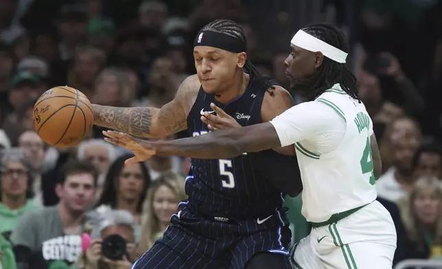 Orlando Magic's Paolo Banchero (5) keeps the ball away from Boston Celtics' Jrue Holiday (4) during the first half in game 1 of a first-round NBA playoff basketball series Sunday, April 20, 2025, in Boston. (AP Photo/Michael Dwyer)
