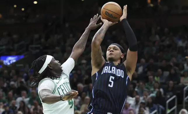 Orlando Magic's Paolo Banchero (5) shoots against Boston Celtics' Jrue Holiday (4) during the second half in Game 1 of a first-round NBA playoff basketball series Sunday, April 20, 2025, in Boston. (AP Photo/Michael Dwyer)