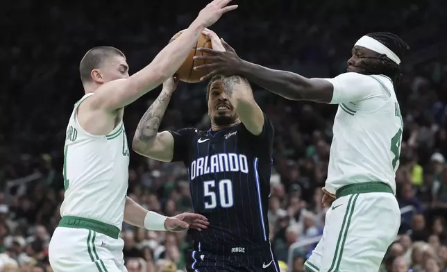 Orlando Magic's Cole Anthony (50) drives between Boston Celtics' Payton Pritchard (11) and Jrue Holiday (4) during the second half in Game 1 of a first-round NBA playoff basketball series Sunday, April 20, 2025, in Boston. (AP Photo/Michael Dwyer)