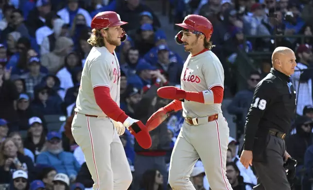 Philadelphia Phillies' Alec Bohm, left, and Bryson Stott high five after they score during the fourth inning of a baseball game against the Chicago Cubs, Saturday, April 26, 2025, in Chicago. (AP Photo/Matt Marton)