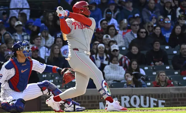 Philadelphia Phillies' Bryce Harper, right, hits a two-RBI double during the fourth inning of a baseball game against the Chicago Cubs, Saturday, April 26, 2025, in Chicago. (AP Photo/Matt Marton)