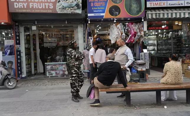 An Indian paramilitary soldier chat with tourists near a clock tower at city centre in Srinagar, Indian controlled Kashmir,Tuesday, April. 22, 2025. (AP Photo/Mukhtar Khan)