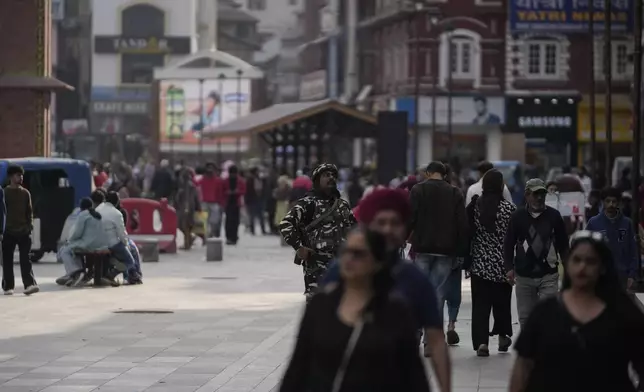 An Indian paramilitary soldier guard as tourists and locals people walk near a clock tower at city centre in Srinagar, Indian controlled Kashmir,Tuesday, April. 22, 2025. (AP Photo/Mukhtar Khan)