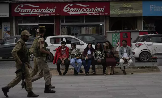 Indian tourists rests on a bench as policemen guard near a clock tower at city centre in Srinagar, Indian controlled Kashmir,Tuesday, April. 22, 2025. (AP Photo/Mukhtar Khan)