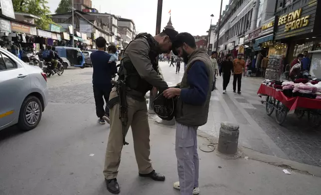 An Indian policeman checks a bag of a civilain near a clock tower at city centre in Srinagar, Indian controlled Kashmir,Tuesday, April. 22, 2025. (AP Photo/Mukhtar Khan)